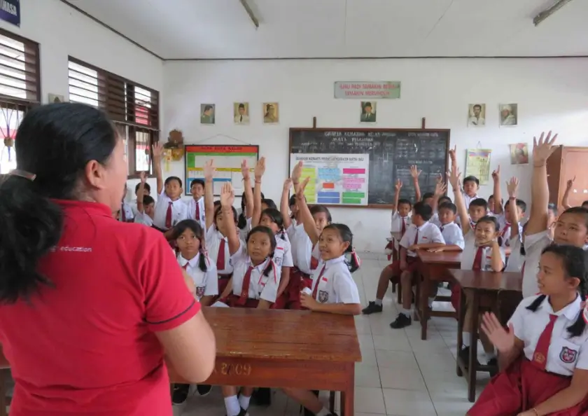 Balinesische Schüler sitzen in Uniform im Klassenzimmer und hören der Lehrerin zu