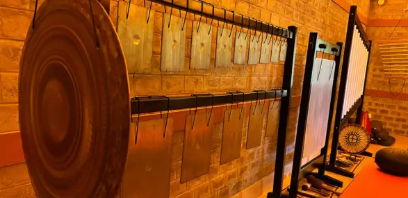 Große Klangschalen hängen an der Wand in einem Raum im Ashram in Indien