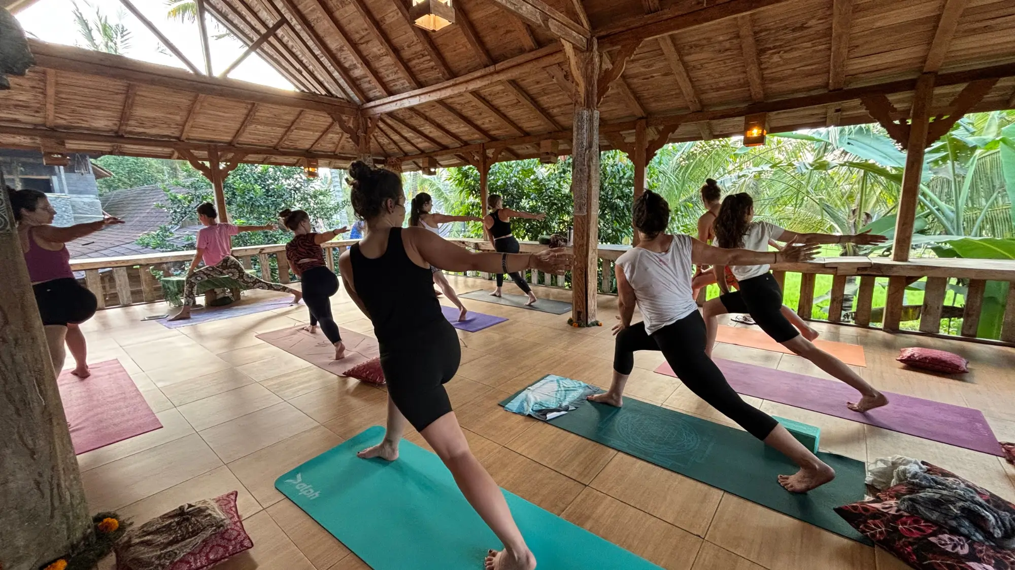Blick in die Yoga Shala des Joglo Organic Hotels, bei der 8 Frauen in Kriegerpose zu sehen sind