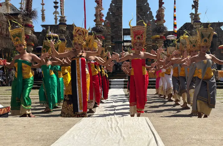 Legong-Tänzerinnen in vielen bunten Kleidern tanzen vor einem Tempel