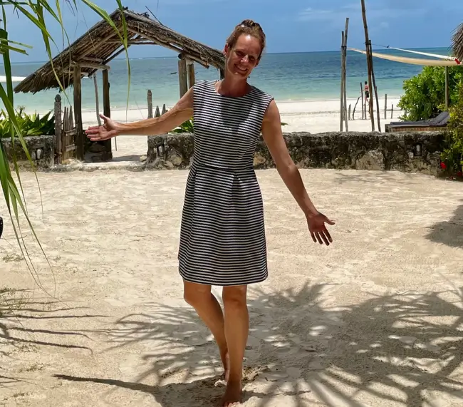 Lisa Weddig steht am Strand von Sansibar und hält die Arme einladend zur Seite