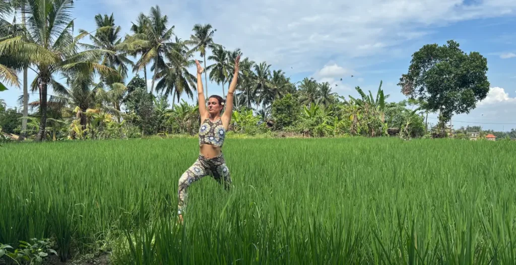 Frau in Yogapose Krieger steht im Reisfeld in Bali