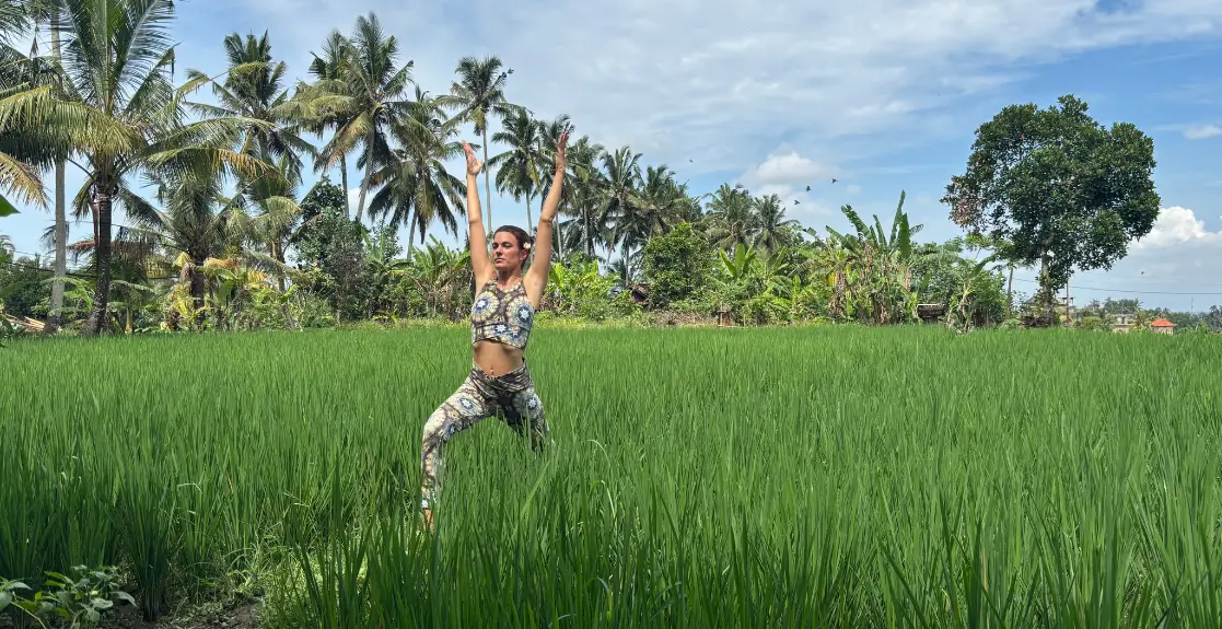 Frau in Yogapose Krieger steht im Reisfeld in Bali