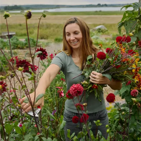 Julia steht in ihrem Garten in Schweden und pflückt Sommerblumen