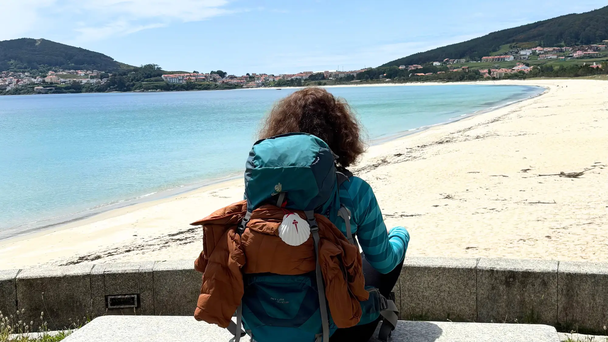 Wanderin Lisa Weddig sitzt in Fisterra beim Jakobsweg Yoga Retreat am Strand und blickt auf das Meer
